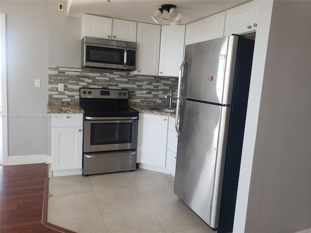 kitchen with backsplash, appliances with stainless steel finishes, sink, white cabinets, and dark stone counters