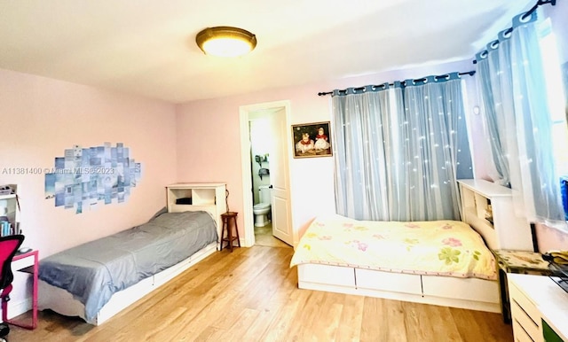 bedroom featuring ensuite bath, multiple windows, and light wood-type flooring