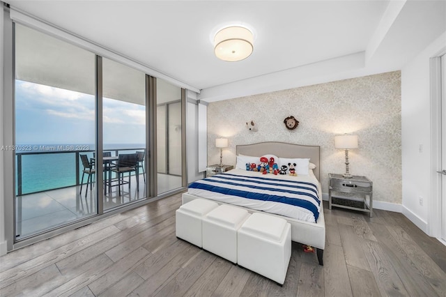 bedroom with expansive windows, access to outside, and light wood-type flooring