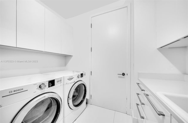 washroom featuring washing machine and dryer, cabinets, tile floors, and sink