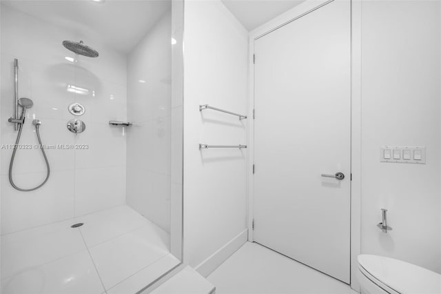 bathroom with toilet, tile flooring, and tiled shower