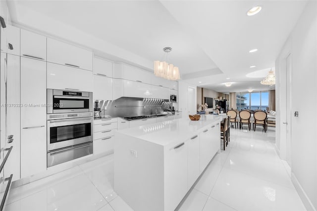 kitchen featuring stainless steel double oven, decorative light fixtures, a notable chandelier, and white cabinets