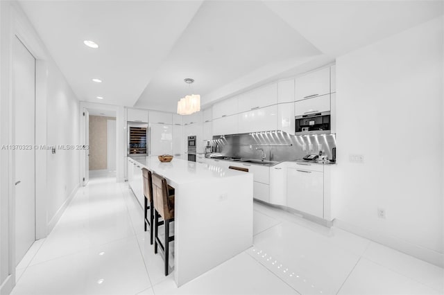 kitchen with a kitchen island, a kitchen breakfast bar, hanging light fixtures, white cabinets, and light tile flooring