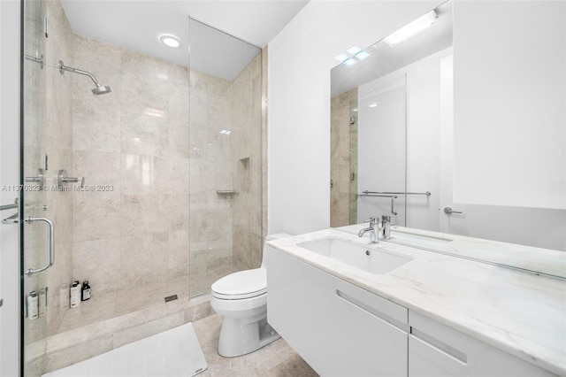 bathroom featuring toilet, vanity, a shower with shower door, and tile flooring