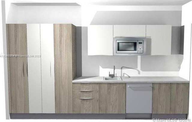 kitchen with white cabinets, white dishwasher, stainless steel microwave, and sink