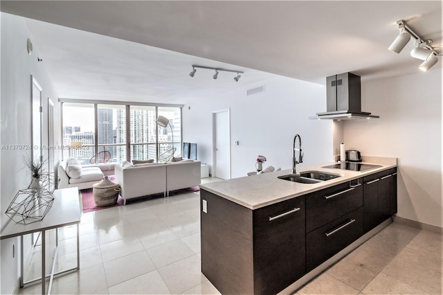 kitchen featuring island exhaust hood, light tile floors, rail lighting, and sink