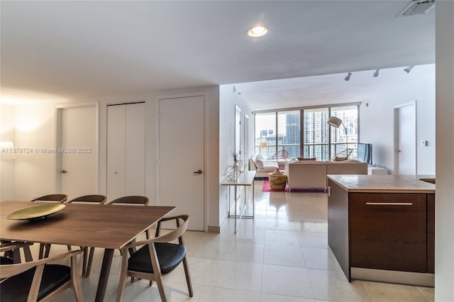 dining space featuring rail lighting and light tile flooring