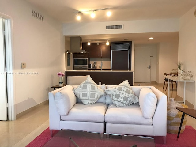 living room with light tile floors, rail lighting, and sink