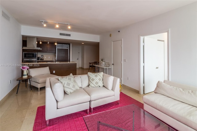 living room with rail lighting, sink, and light tile flooring