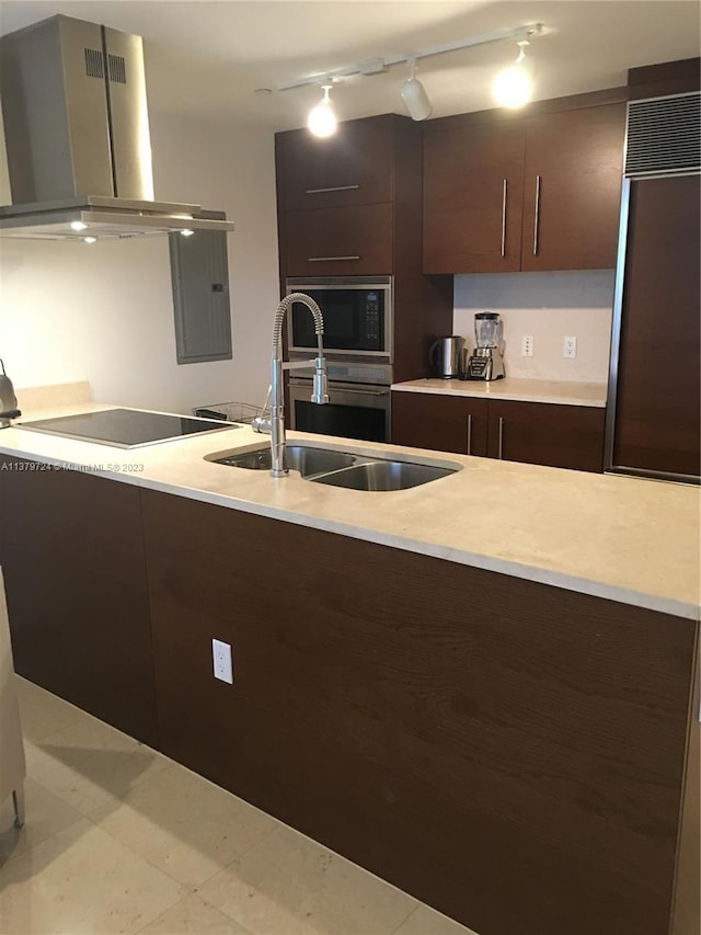 kitchen featuring light tile floors, island exhaust hood, dark brown cabinets, track lighting, and black appliances