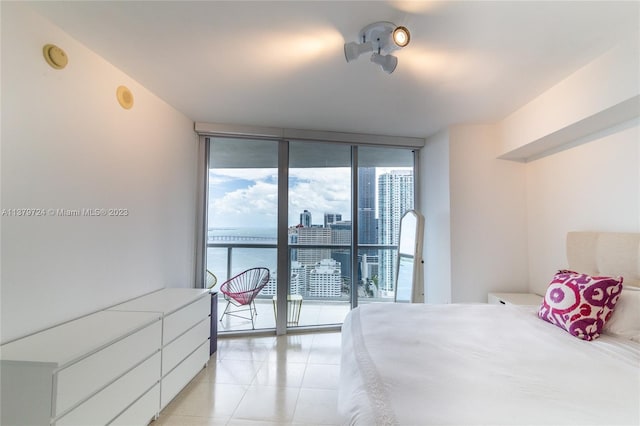 bedroom with access to exterior, a wall of windows, and light tile floors