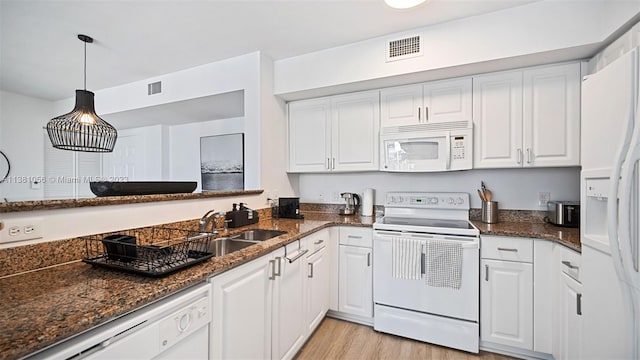 kitchen featuring white appliances, dark stone counters, decorative light fixtures, white cabinetry, and light wood-type flooring