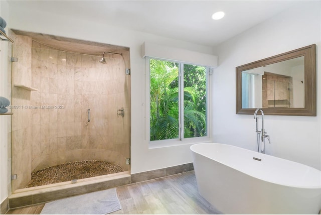 bathroom featuring plus walk in shower and wood-type flooring