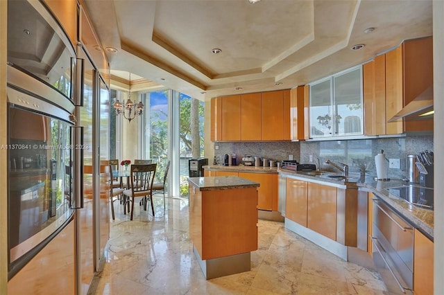 kitchen with a kitchen island, a tray ceiling, black electric cooktop, and tasteful backsplash