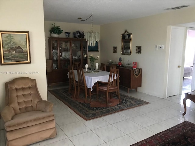 tiled dining room with a chandelier