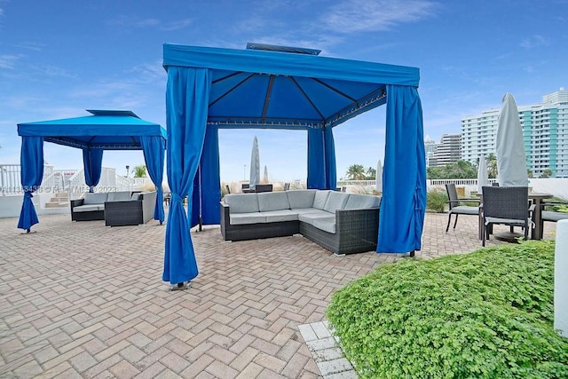 view of patio with outdoor dining space, a city view, an outdoor living space, and a gazebo