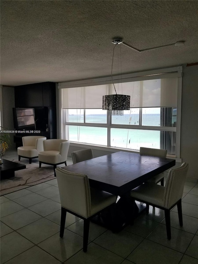 dining room with tile patterned flooring, a water view, and a textured ceiling