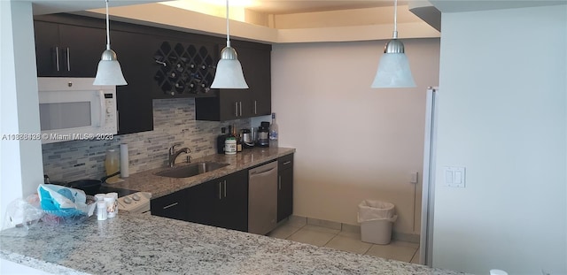 kitchen featuring light tile patterned floors, white microwave, backsplash, stainless steel dishwasher, and a sink