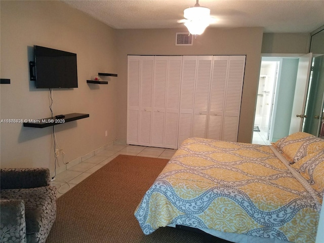 bedroom featuring a closet, visible vents, a ceiling fan, a textured ceiling, and tile patterned flooring