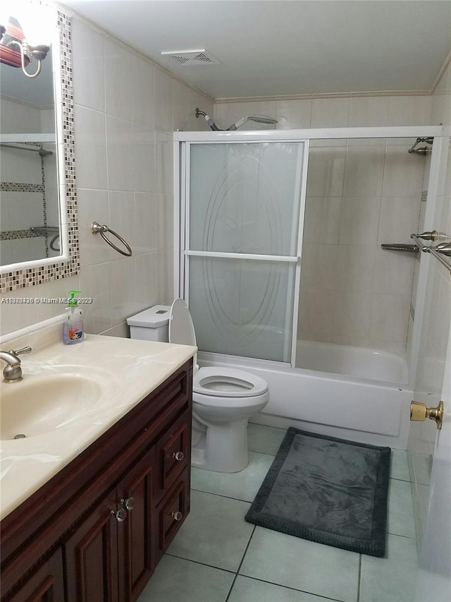 bathroom featuring visible vents, shower / bath combination with glass door, tile patterned floors, vanity, and tile walls