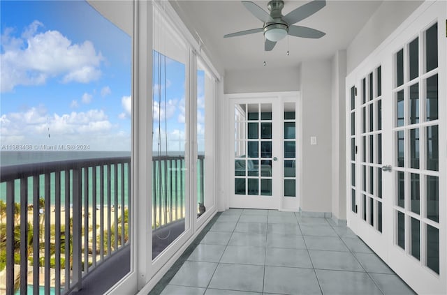 unfurnished sunroom with ceiling fan and a water view