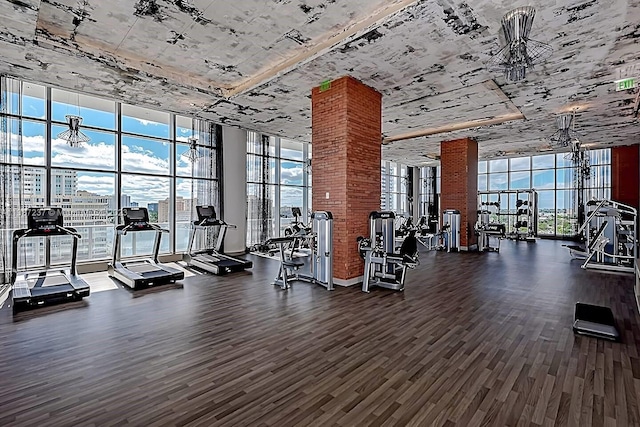 gym with brick wall, floor to ceiling windows, and dark hardwood / wood-style flooring