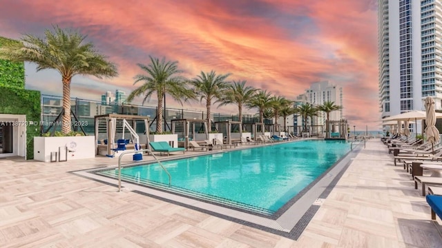 pool at dusk featuring a patio