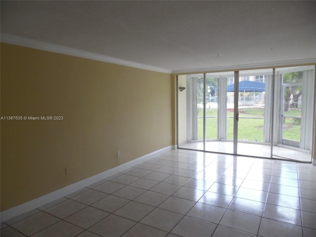 spare room with tile floors, ornamental molding, and expansive windows