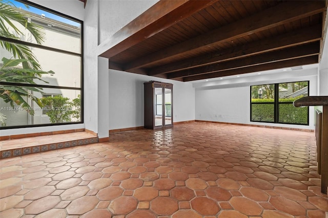 unfurnished living room featuring beam ceiling, wooden ceiling, and light tile flooring