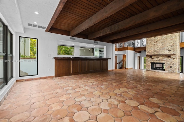 unfurnished living room with light tile floors, a fireplace, brick wall, beam ceiling, and wood ceiling