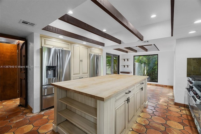 kitchen with light tile floors, butcher block counters, appliances with stainless steel finishes, and beam ceiling