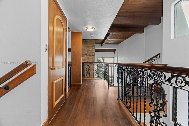 corridor with dark hardwood / wood-style floors, wood ceiling, a textured ceiling, and beamed ceiling