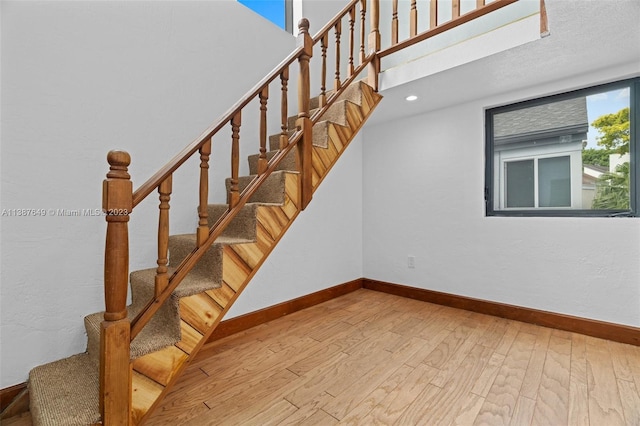 staircase with a textured ceiling and light wood-type flooring