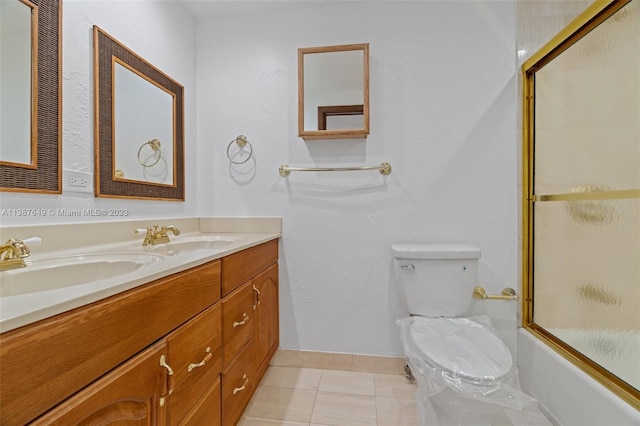 full bathroom featuring toilet, large vanity, double sink, combined bath / shower with glass door, and tile flooring