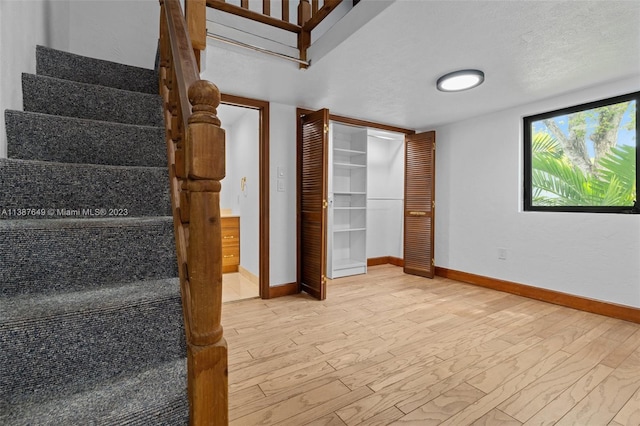 stairway with a textured ceiling and light hardwood / wood-style flooring