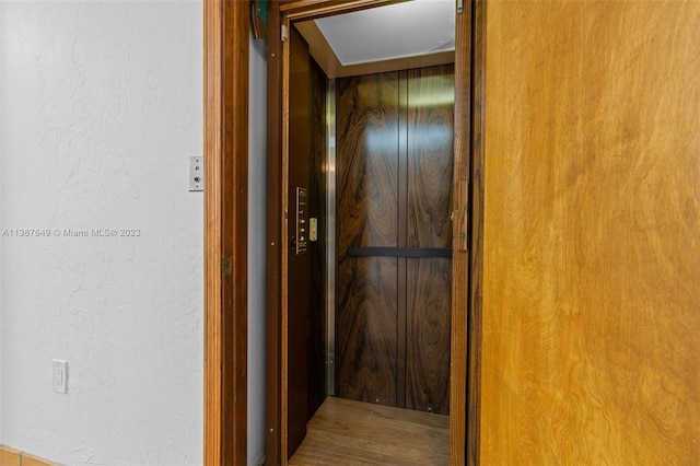 corridor with elevator and wood-type flooring