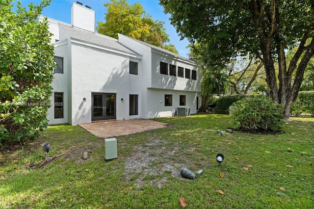 rear view of property featuring a lawn, central AC, a patio area, and french doors