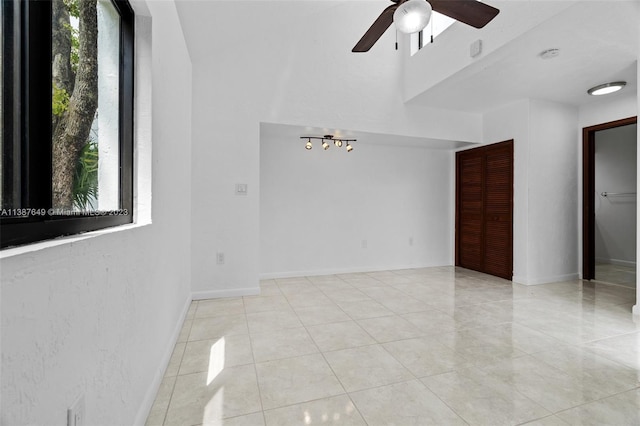 spare room with a healthy amount of sunlight, ceiling fan, and light tile floors