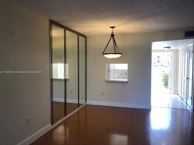 spare room featuring a textured ceiling and dark hardwood / wood-style flooring