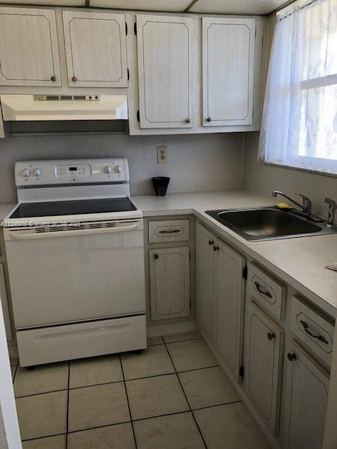 kitchen with sink, white electric stove, and light tile flooring