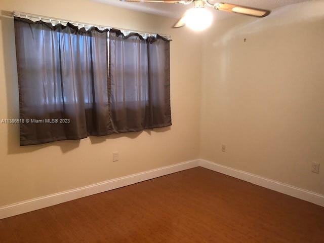 unfurnished room featuring ceiling fan and dark hardwood / wood-style flooring