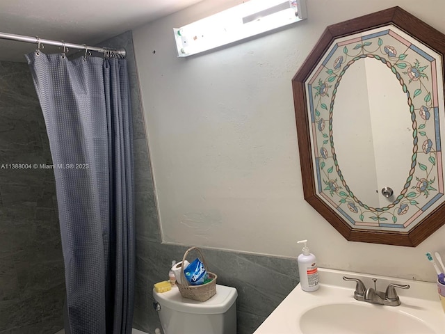 bathroom with toilet, sink, and tile walls