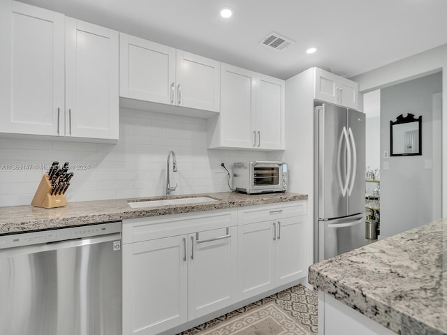 kitchen with white cabinetry, stainless steel appliances, sink, and light stone countertops