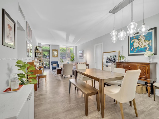 dining space featuring light wood-type flooring and expansive windows