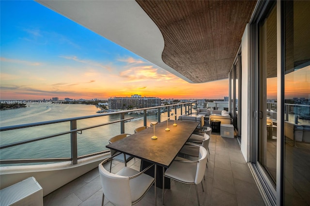 balcony at dusk featuring a water view