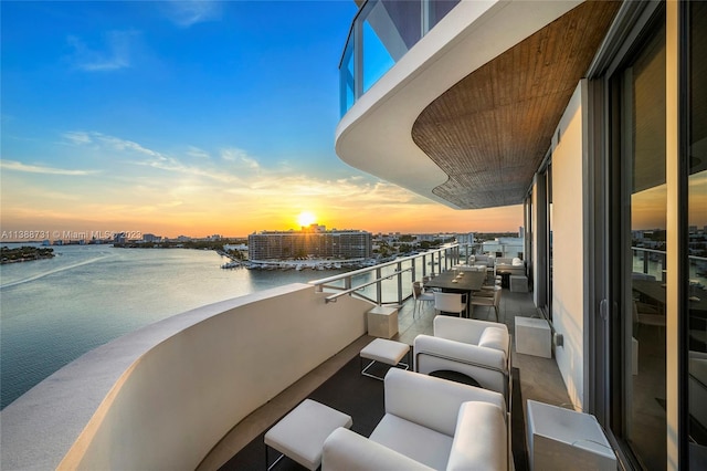 balcony at dusk featuring a water view and outdoor lounge area