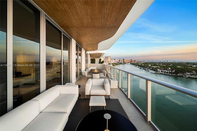 balcony at dusk with an outdoor living space and a water view