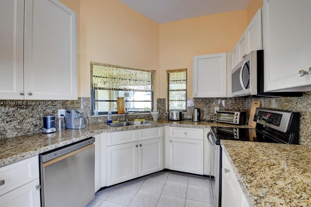 kitchen featuring appliances with stainless steel finishes, white cabinetry, backsplash, and sink