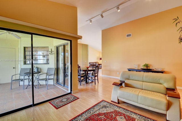 living room featuring high vaulted ceiling, ceiling fan, light hardwood / wood-style flooring, and rail lighting