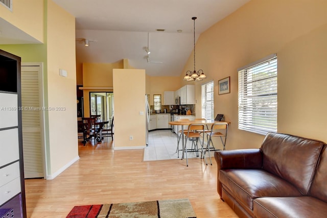 living room featuring a notable chandelier, high vaulted ceiling, and light hardwood / wood-style floors